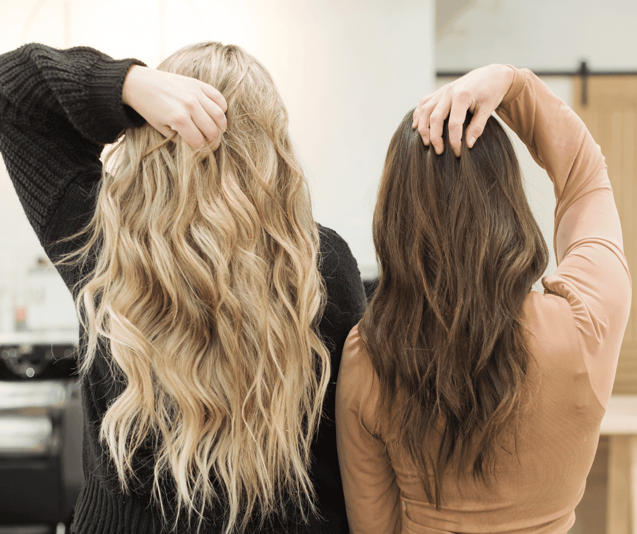 Two women showing blond and brown wavy hairstyles, view from the back.