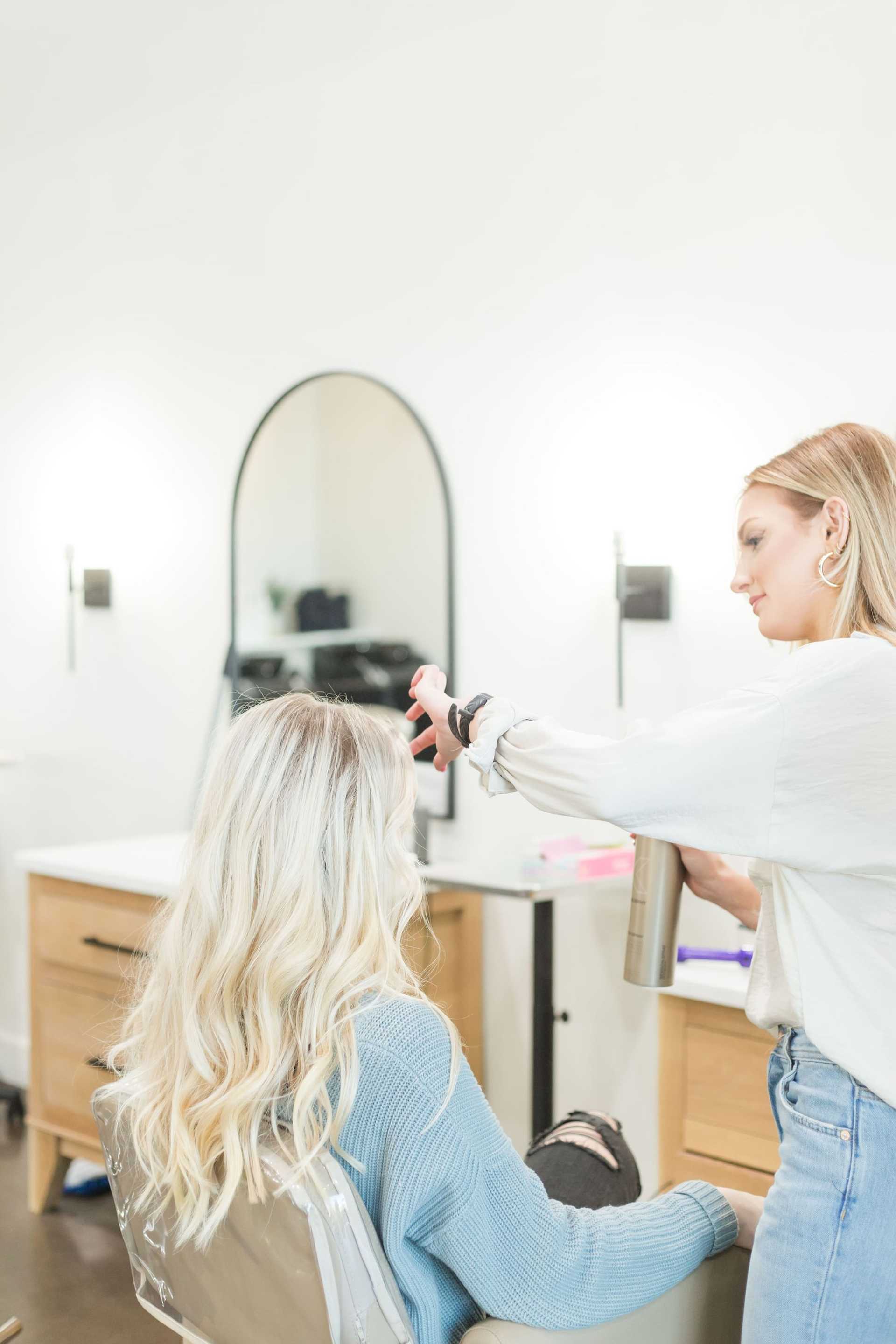 Hairstylist applying product to client's hair in a modern salon setting.
