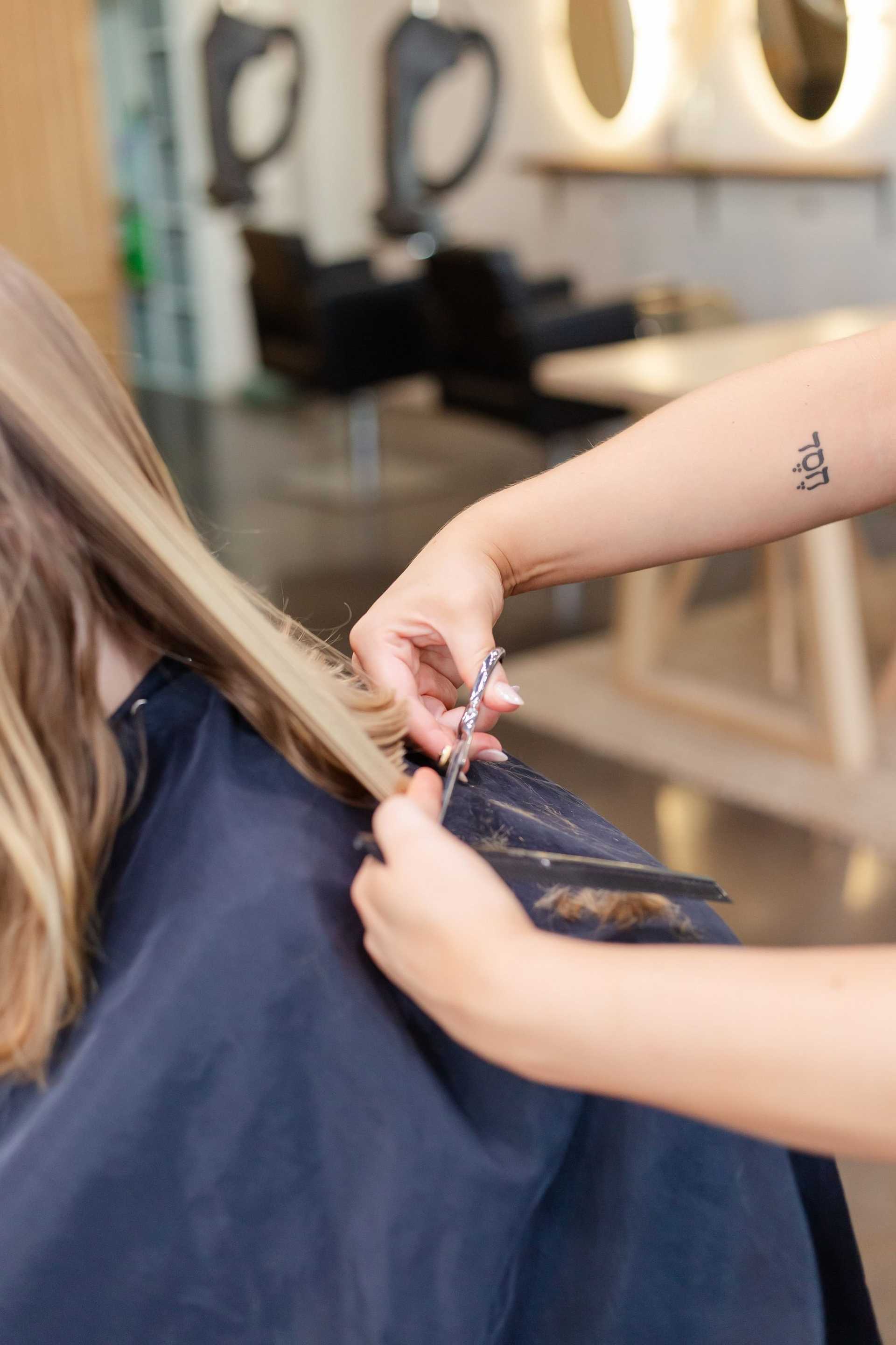 Hairdresser cutting long blond hair in a salon.